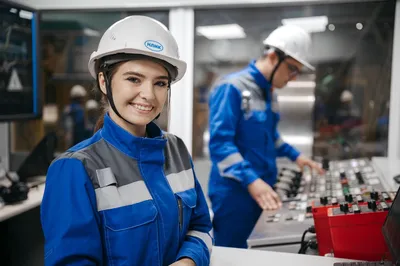 Confident female engineer smiling in an industrial control room. Teamwork and safety in operations.